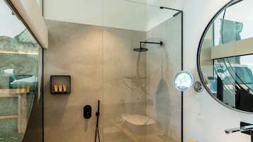 Ein modernes Badezimmer mit einer gläsernen Duschkabine, einem Holzwaschtisch und einem großen Spiegel.