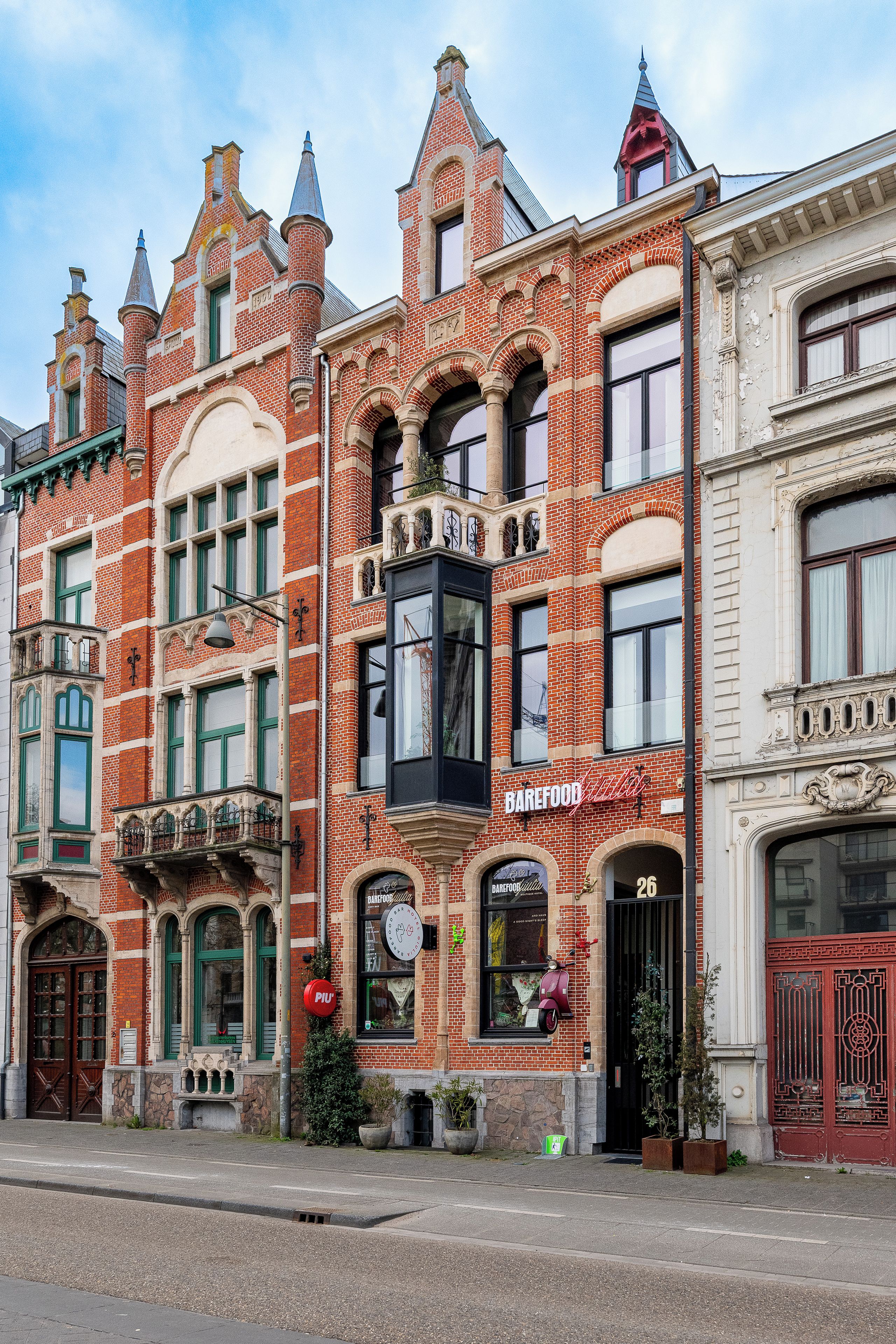 En rad historiska byggnader med distinkta arkitektoniska drag, inklusive en framträdande fasad av rött tegel och utsmyckade detaljer.