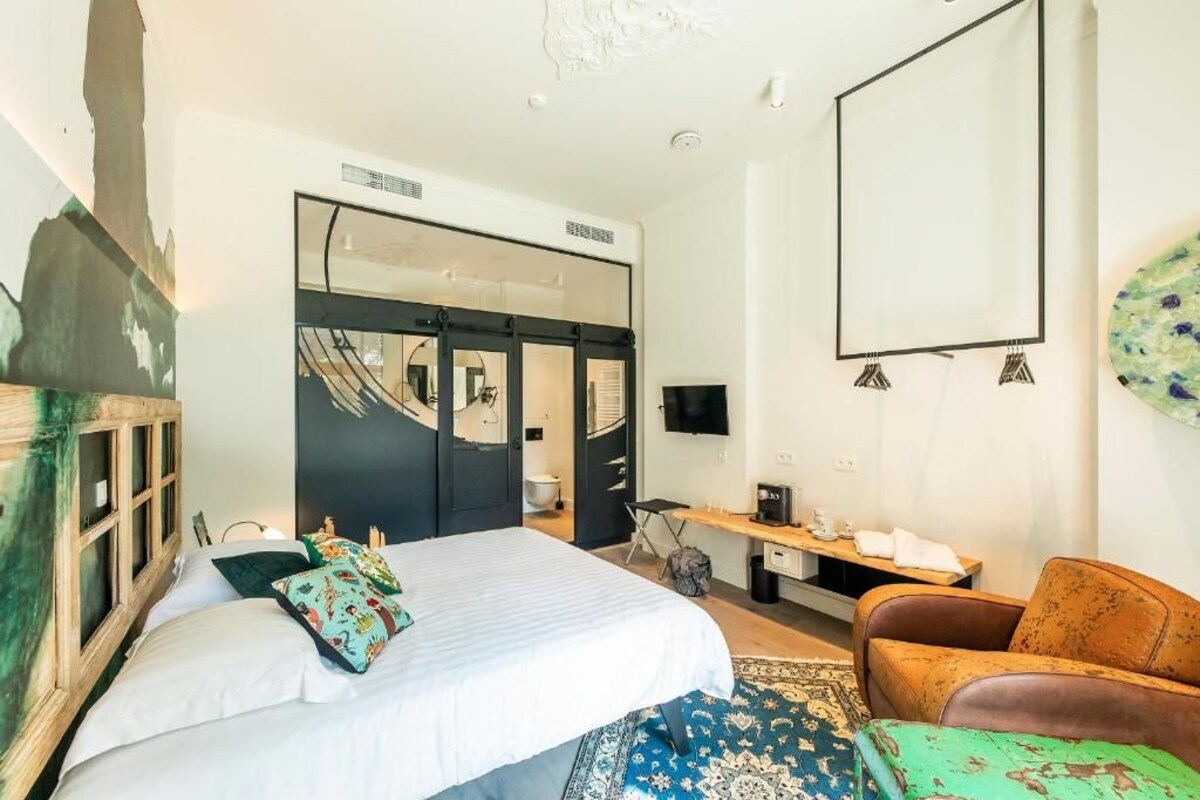 A bedroom with a bed, a chair, a desk, a television, and a wardrobe.