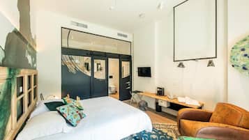 Een slaapkamer met een bed, een stoel, een bureau, een televisie en een kledingkast.