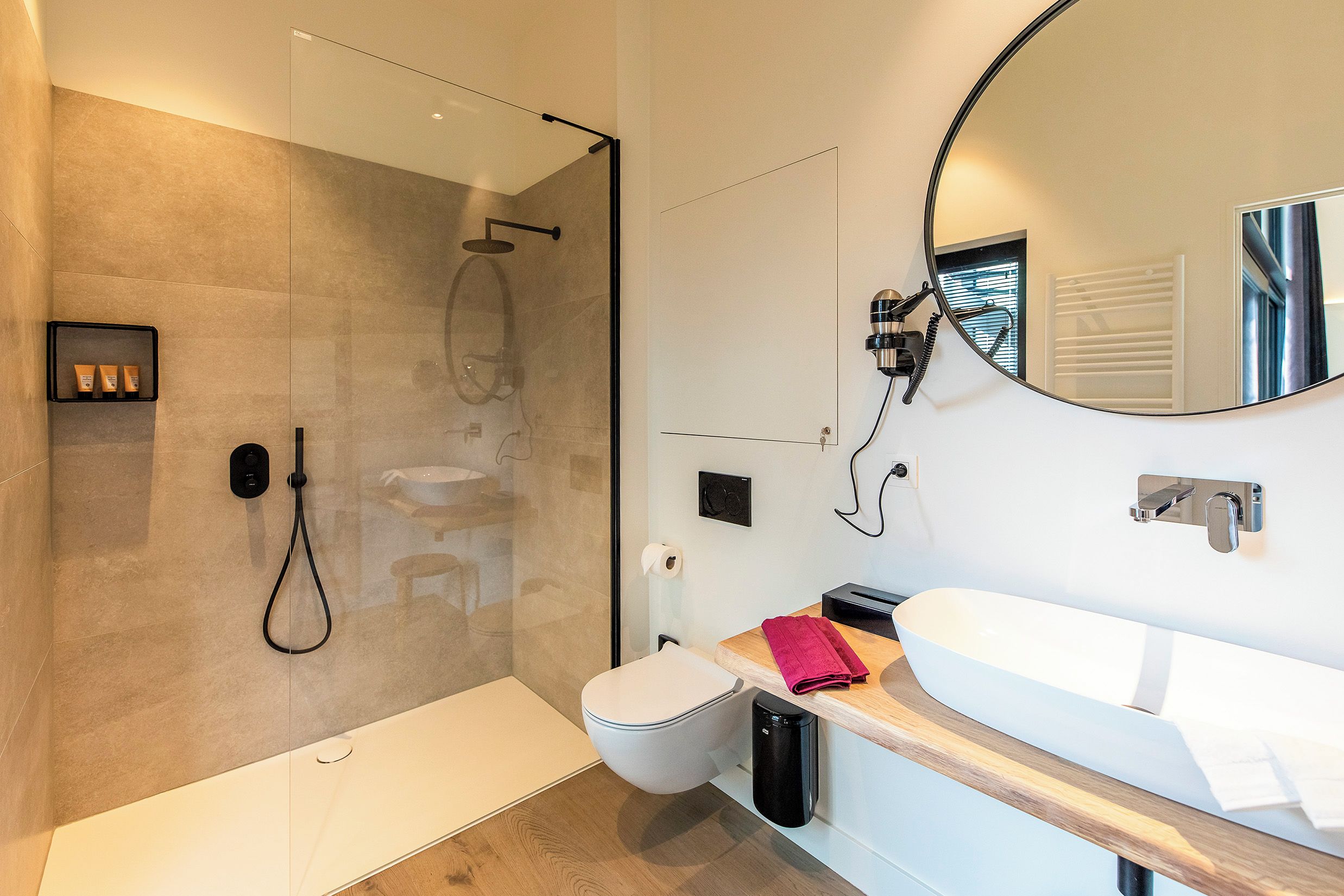 Een moderne badkamer met een douchecabine van glas, een wit wastafelmeubel en een grote spiegel.