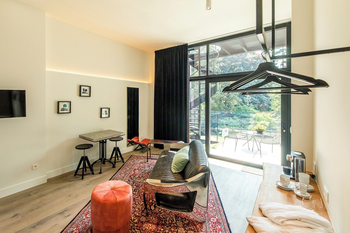 A modern living room with a sofa, ottoman, coffee table, and a dining area with chairs and a table.
