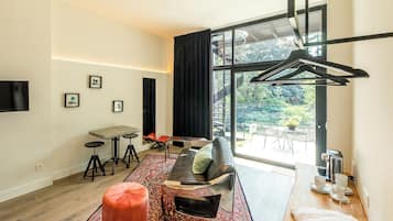 Ein modernes Wohnzimmer mit einer Couch, Hocker, Couchtisch und einem Essbereich mit Stühlen und Tisch.