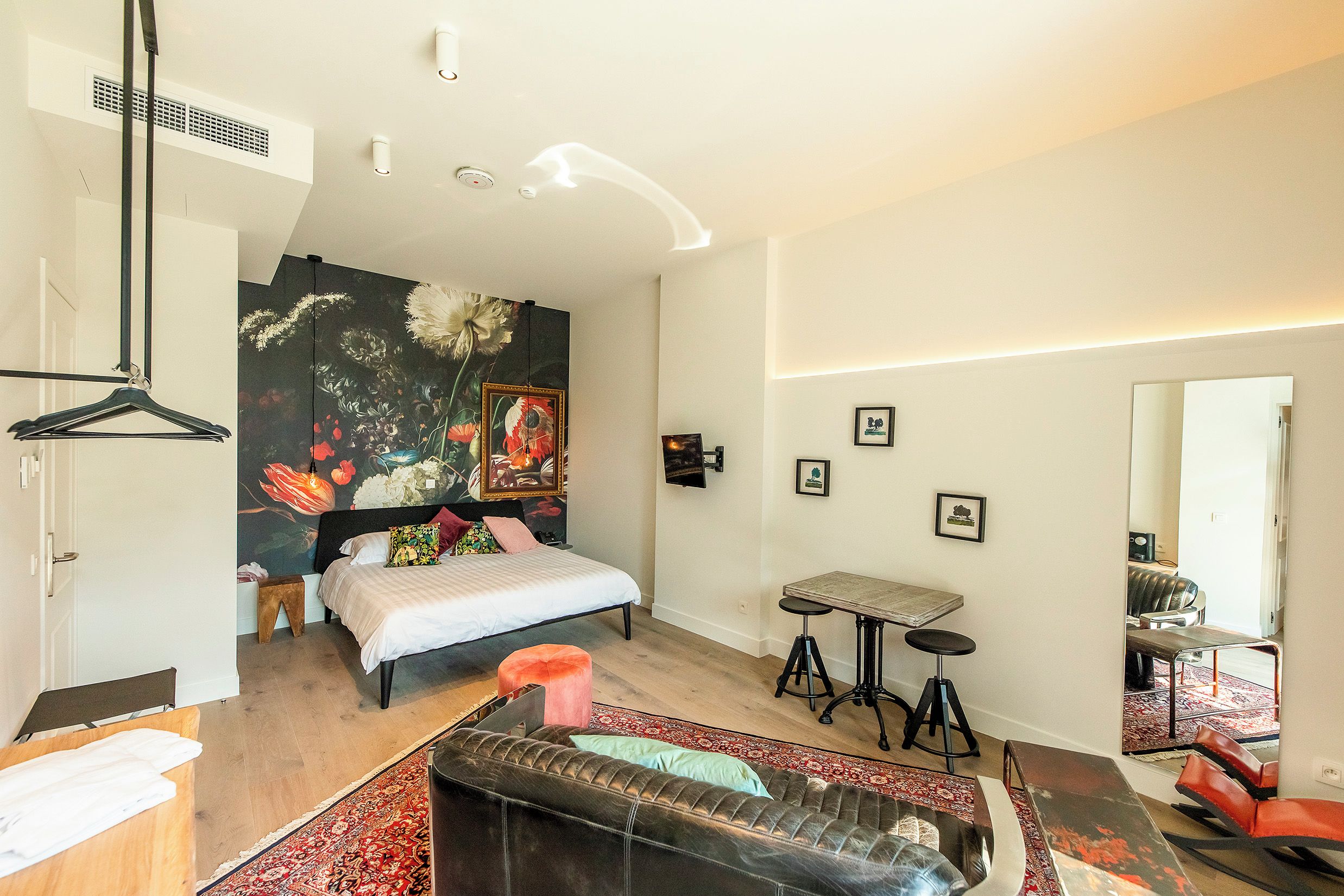 Un dormitorio moderno con una cama, un sofá, una mesita y un espejo.