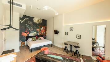 Une chambre moderne avec un lit, un canapé, une petite table et un miroir.