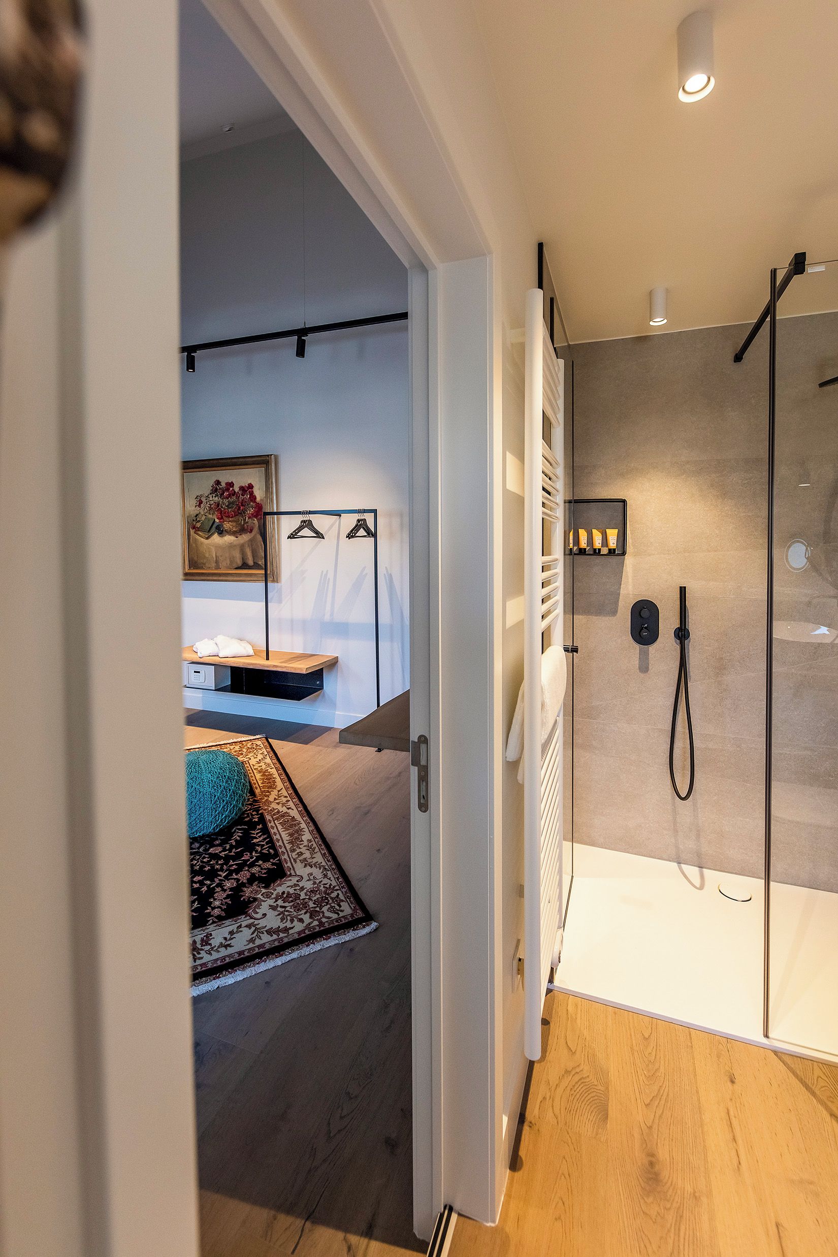 A modern bathroom with a glass shower enclosure, a towel rack, and a small shelf with toiletries.