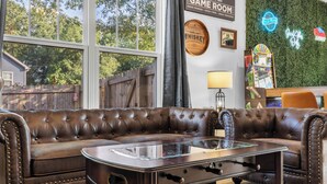 Een bruine leren modulaire bank met een glazen salontafel, een houten bord waarop staat 