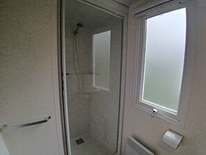 Ein Badezimmer mit Dusche, Toilette und Fenster.