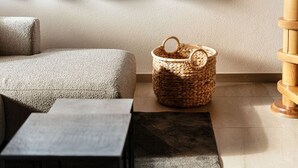 A corner of a room with a woven basket, a textured sofa, and a small table.