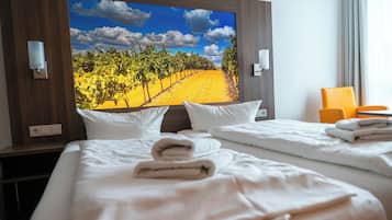 Habitación de hotel con dos camas, un televisor grande mostrando un viñedo y una ventana con cortinas.