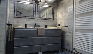 A bathroom with a double vanity, two mirrors, a towel rack, and a white door. - mas val-chenaie (Gordes)