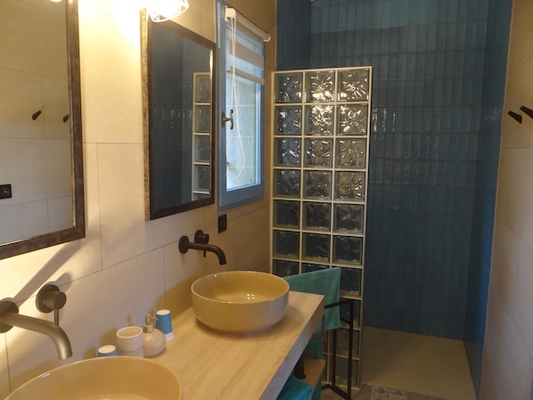 A bathroom with a large mirror, two sinks, and a shower with a glass door. - mas val-chenaie (Gordes)