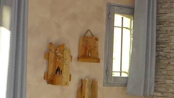 Ein Zimmer mit einer Steinsäule, einem Fenster mit Vorhang und drei Holzarbeiten an der Wand.