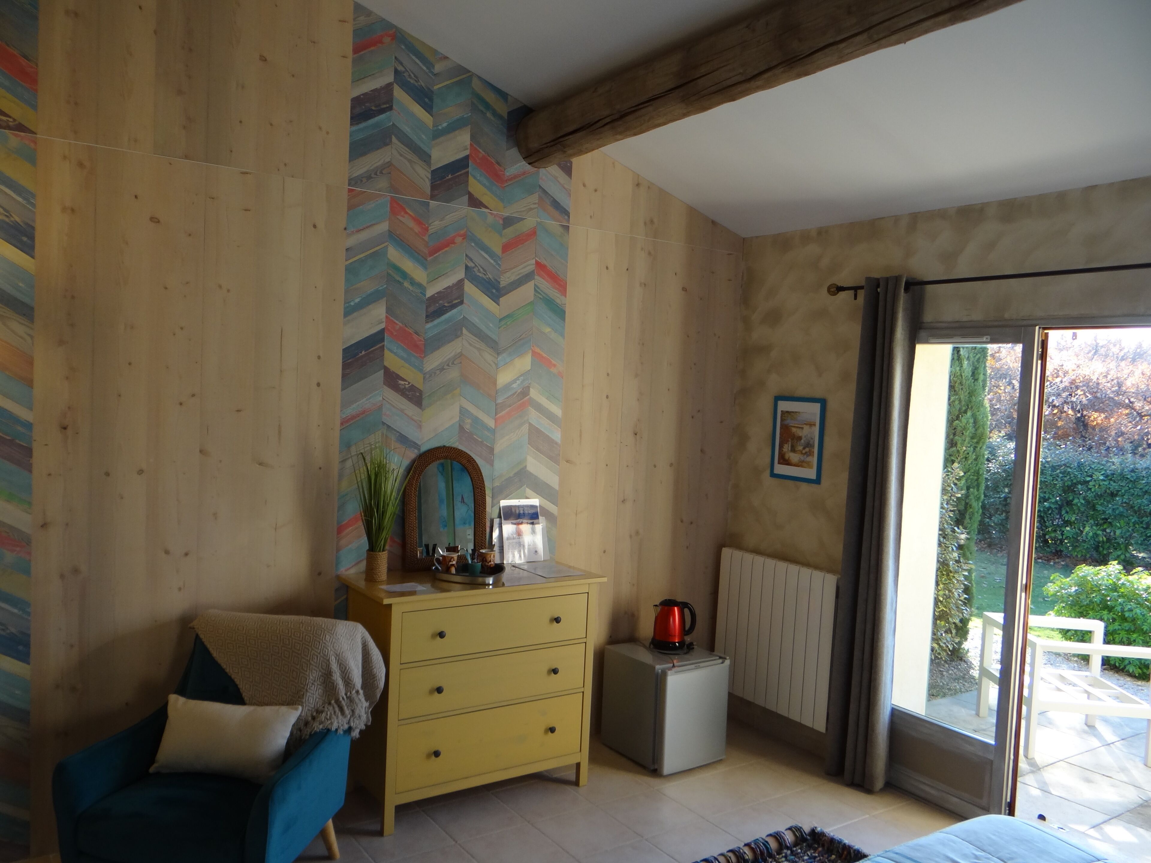 Una habitación con paredes de madera, un revestimiento mural en patrón de espiga, un aparador, una silla, un radiador y vistas al exterior.