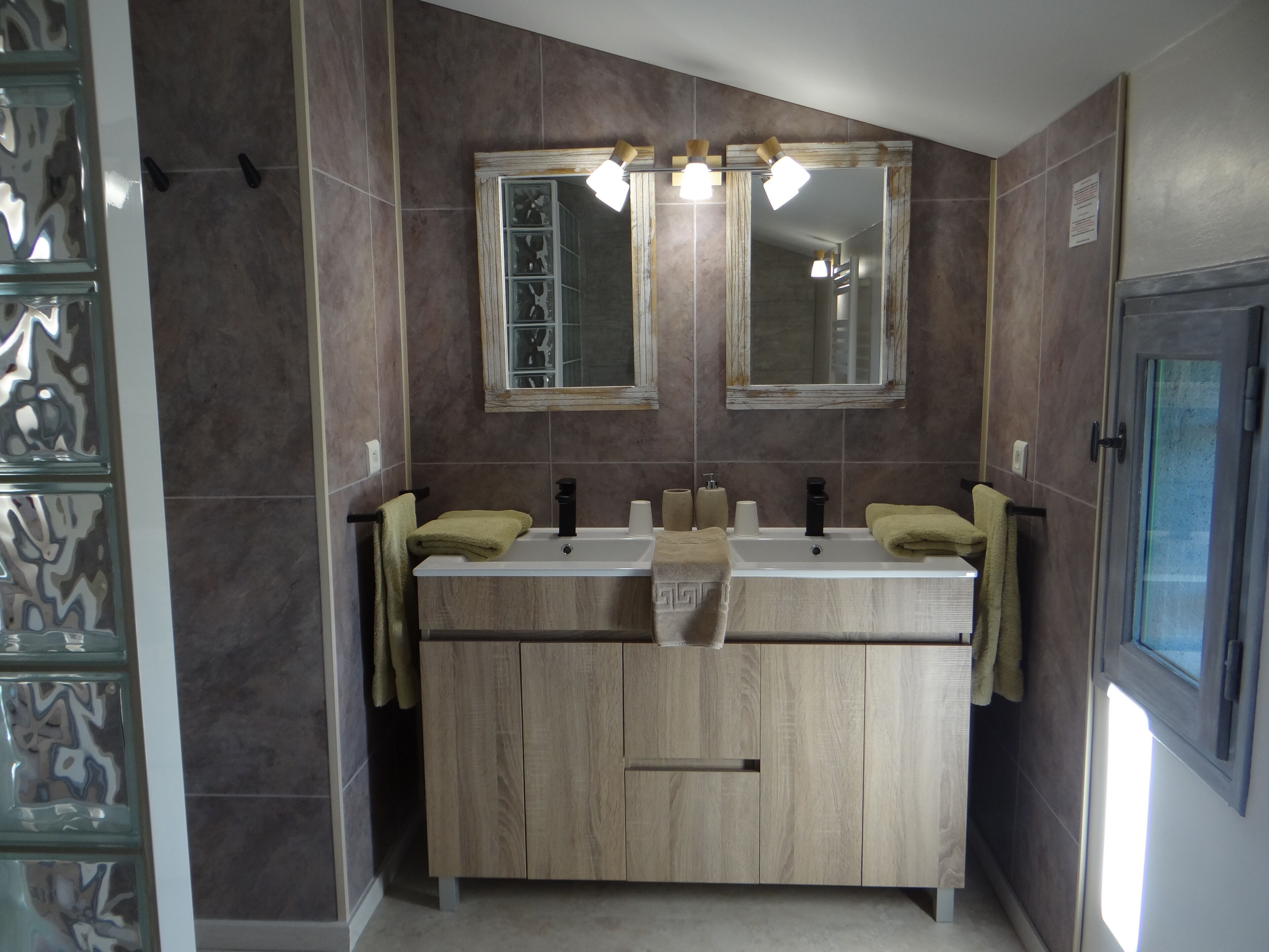 A bathroom with a wooden vanity, two sinks, and a mirror above.