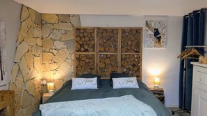 Ein Schlafzimmer mit Steinwand, einem Bett mit zwei Kissen, einem Holz-Kopfteil und einem Kleiderschrank.