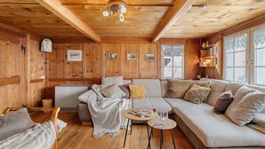 L'intérieur d'un chalet en bois, avec un canapé, une petite table et un lit.