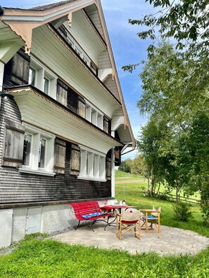 Ein mehrstöckiges Gebäude mit einem Balkon, einer roten Bank und einem kleinen Tisch mit Stühlen.