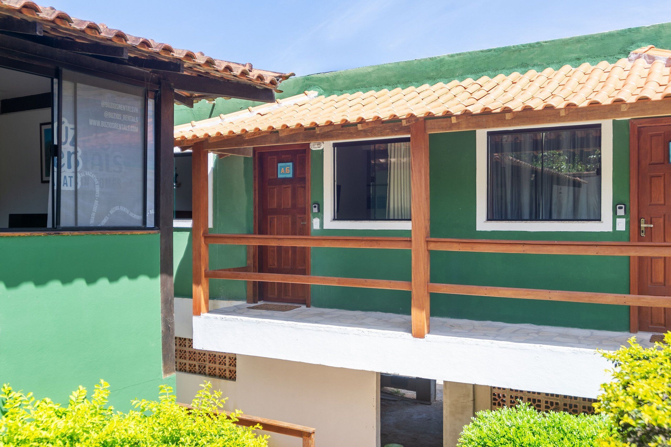 A two-story building with a green exterior, a wooden balcony, and a tiled roof.