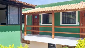 A two-story building with a green exterior, a wooden balcony, and a tiled roof.
