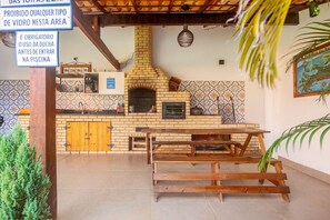 A kitchen with a brick oven, wooden benches, and tiled walls. - Arpoador Praia & Piscina Buzios Rentals (Buzios)