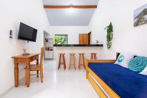 A room with a bed, a desk, a TV, and a kitchenette. - Arpoador Praia & Piscina Buzios Rentals (Buzios)