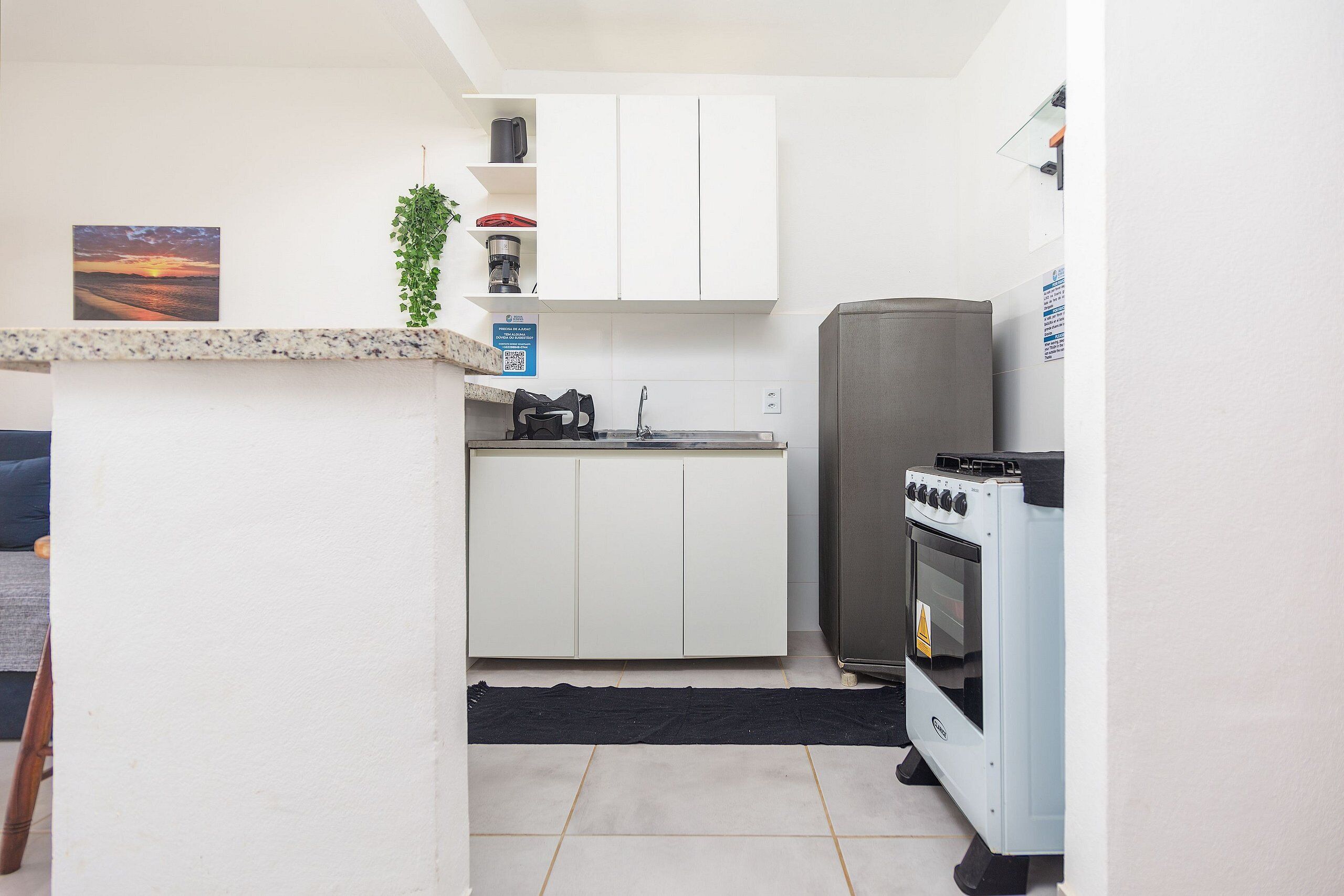 A compact kitchen with white cabinets, a built-in oven, and a coffee maker on the countertop.