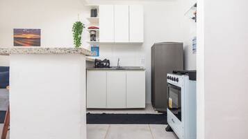 A compact kitchen with white cabinets, a built-in oven, and a coffee maker on the countertop.