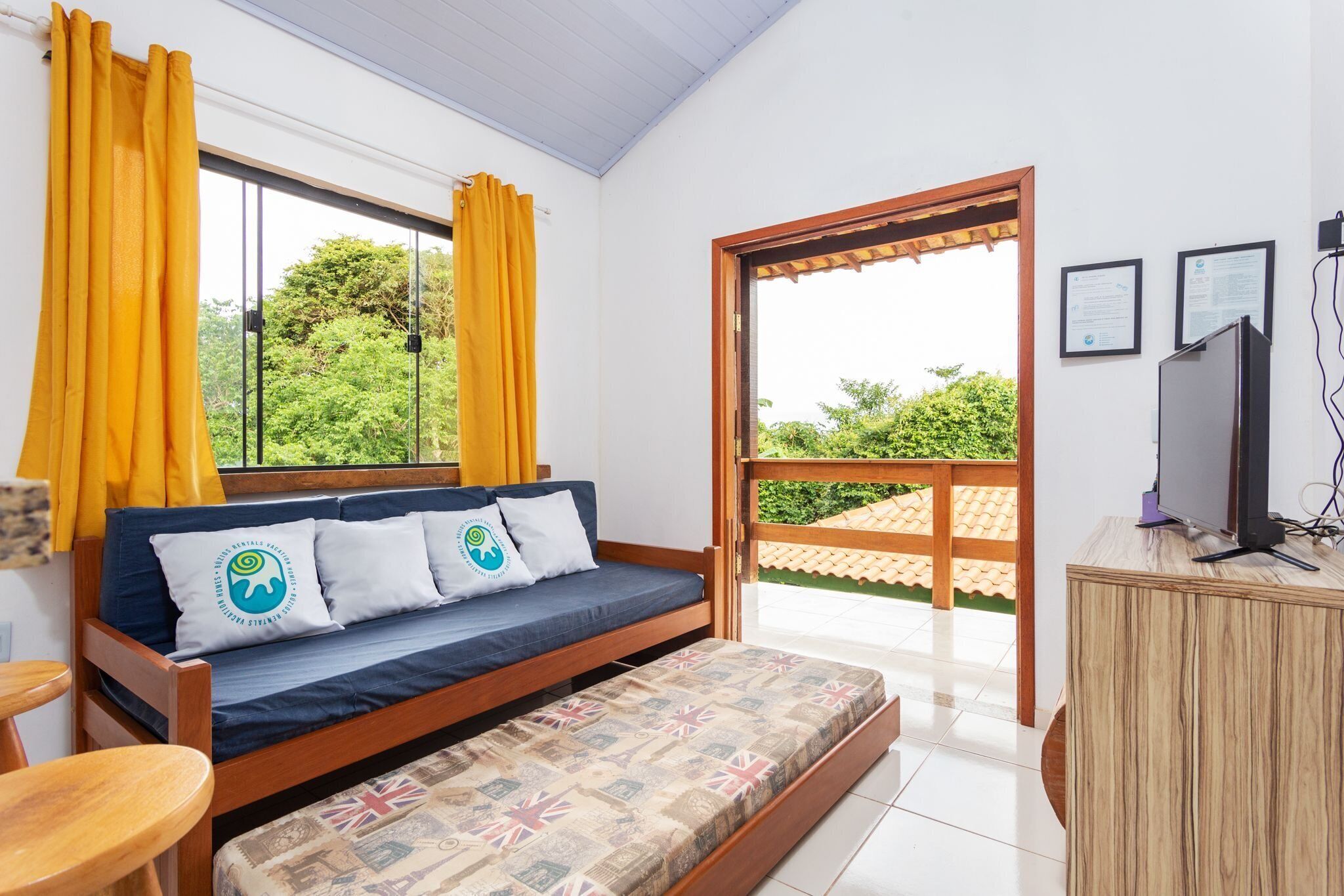 A room with a sofa bed, a small table, a TV, and a wooden cabinet.