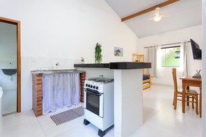 Een compacte keuken met een gasfornuis, oven en een klein eethoekje met een tafel en stoelen.