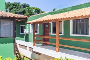 A green building with a tiled roof, a wooden porch, and a door marked 'A6'. - Arpoador Praia & Piscina Buzios Rentals (Buzios)