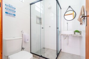 Une salle de bain avec une douche à parois de verre, des toilettes, un lavabo avec un miroir et un porte-serviettes.