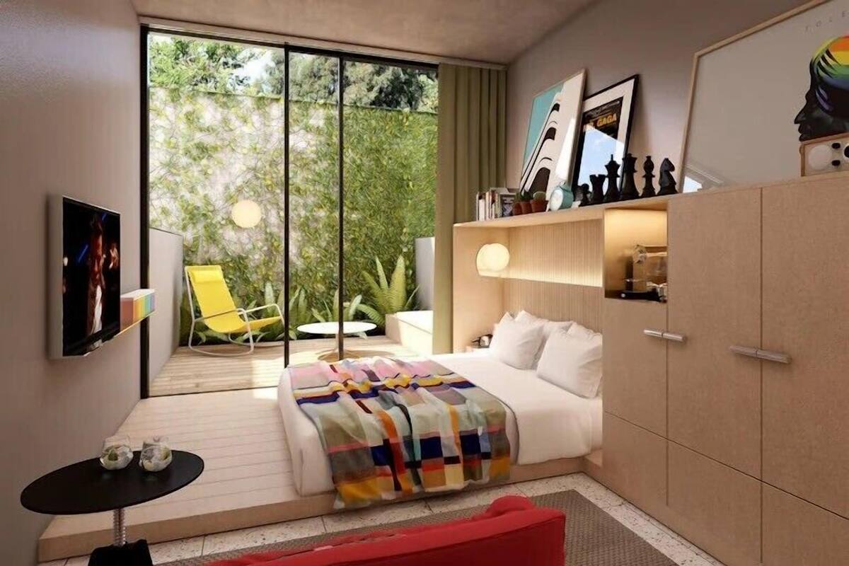 Una camera da letto moderna con un letto, una TV, una sedia e un armadio.