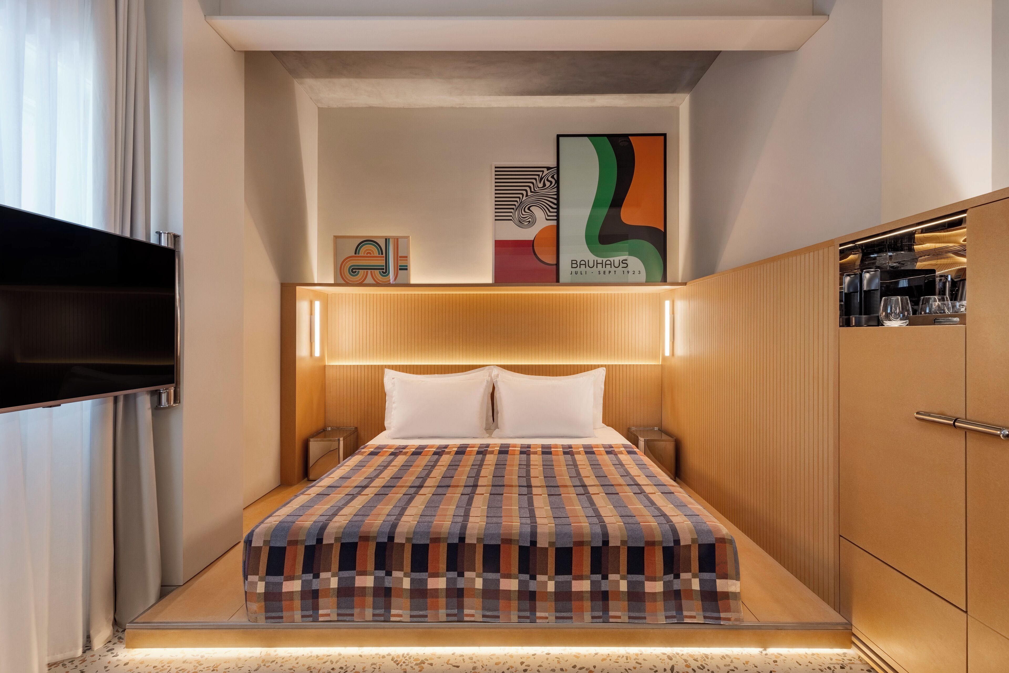 Une chambre d’hôtel moderne dotée d’un grand lit, d’un téléviseur à écran plat, d’une armoire en bois et d’une œuvre d’art accrochée au mur.