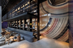 A modern interior with a central seating area, bookshelves, and a distinctive curved wall design. - Dizengoff 99 by Isrotel Design (Tel Aviv)