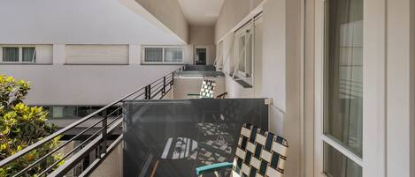 A modern building with a balcony, a staircase, and a view of another building.
