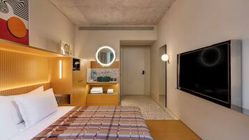 Een hotelkamer met een bed, een televisie, een badkamer met een spiegel en een deur die naar een andere kamer leidt.