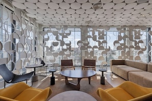 A modern interior with a geometric ceiling design, large windows, and contemporary furniture. - Dizengoff 99 by Isrotel Design (Tel Aviv)