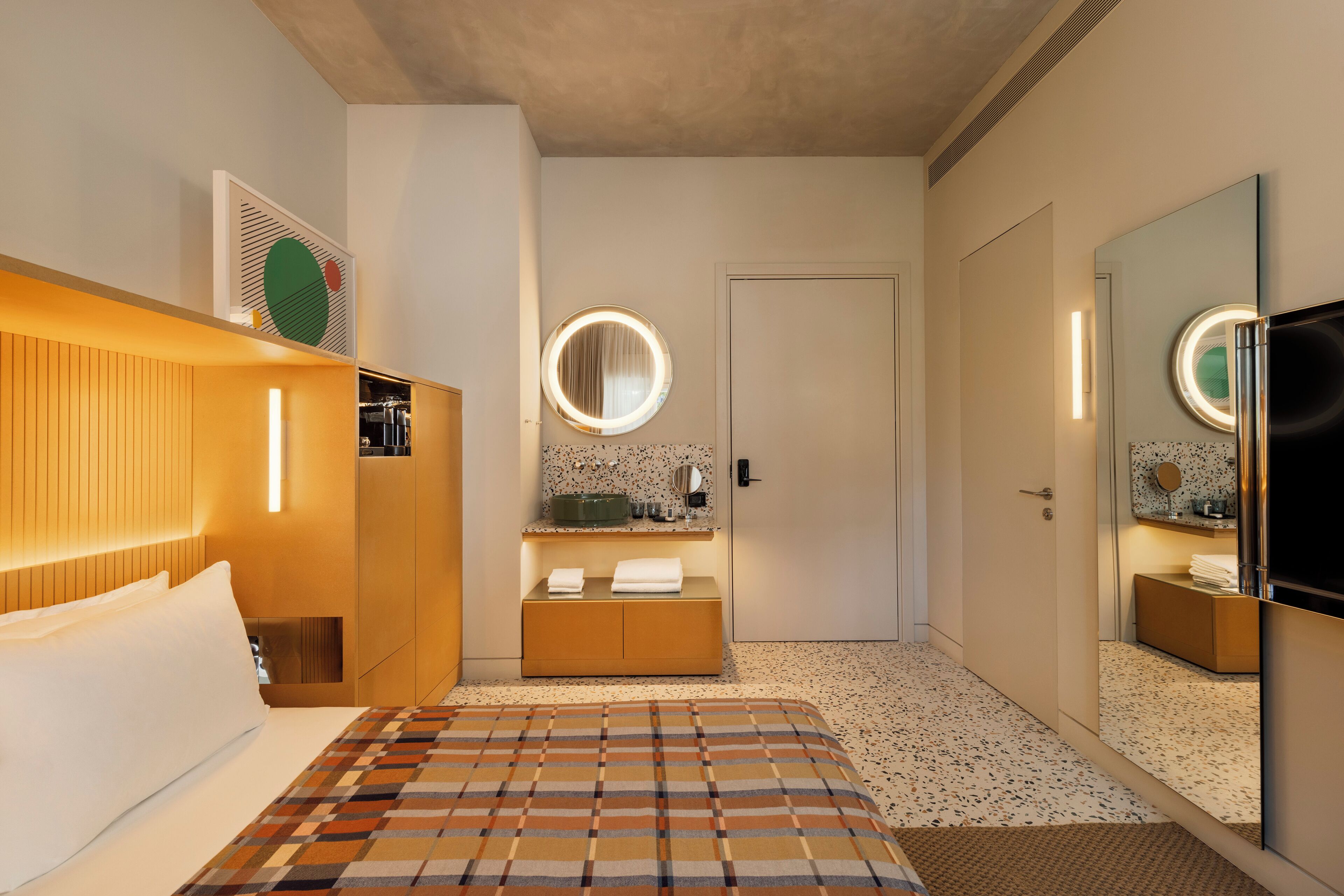 Ein Hotelzimmer mit Bett, Nachttisch, Spiegel, Kleiderschrank und Fernseher.