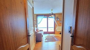 Un pasillo de madera que conduce a una sala de estar con un sofá, una alfombra y un ventilador de techo.