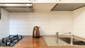 A kitchen with white tiled walls, a stainless steel sink, a gas stove, and a kettle. - GuestHost - Comfortable and practical 22 square meters studio apartment, perfect for two people, located on the second floor of a building without an elevator.The property is located in the Corvetto neighborhood, a lively area characterized by green spac (Milan)