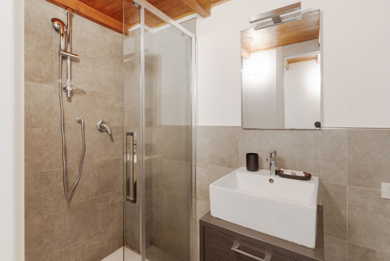Une salle de bain moderne avec une douche à parois de verre, un lavabo blanc et un plafond en bois.