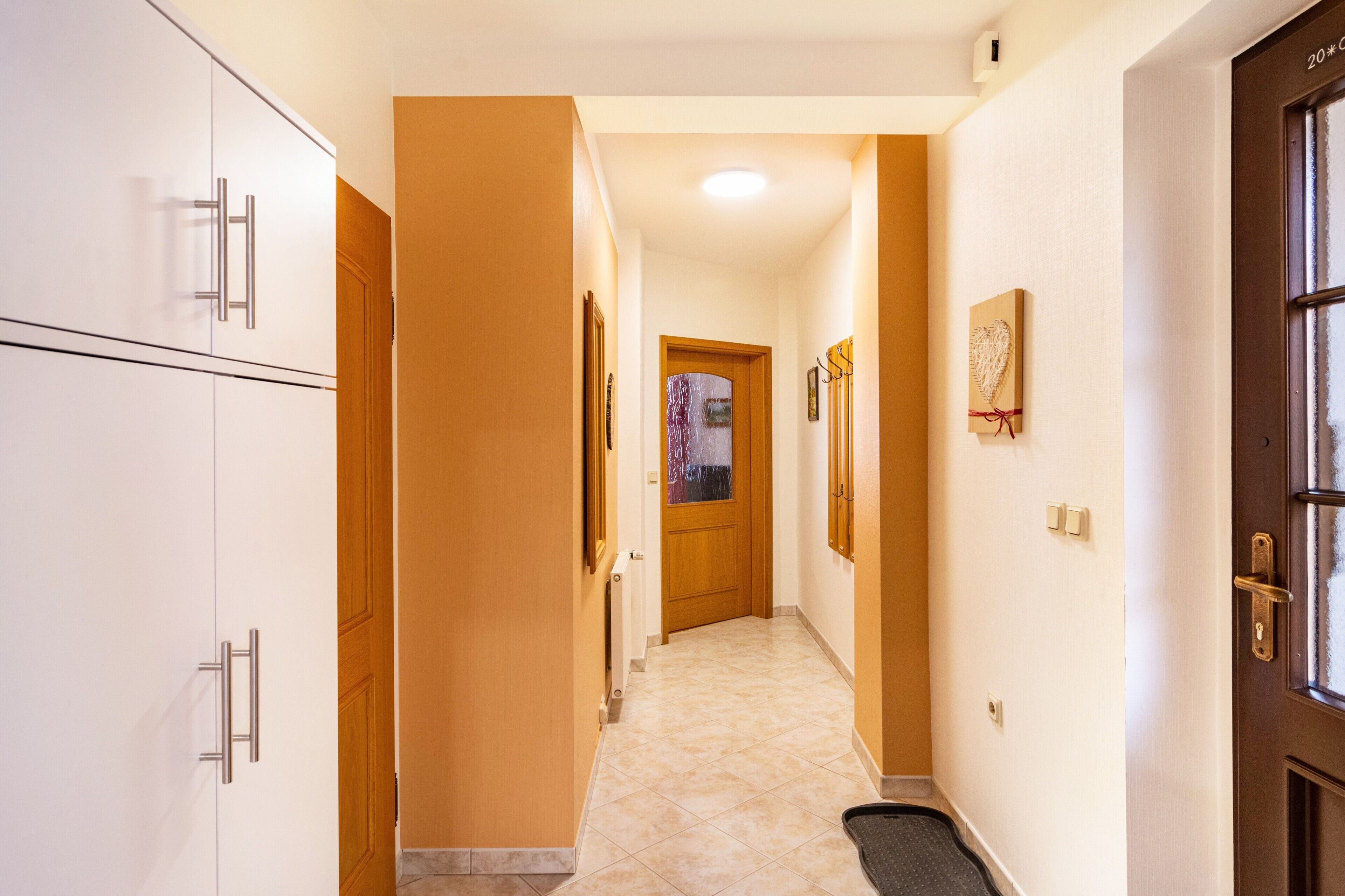 A hallway with a wooden door, a radiator, and a picture frame on the wall.