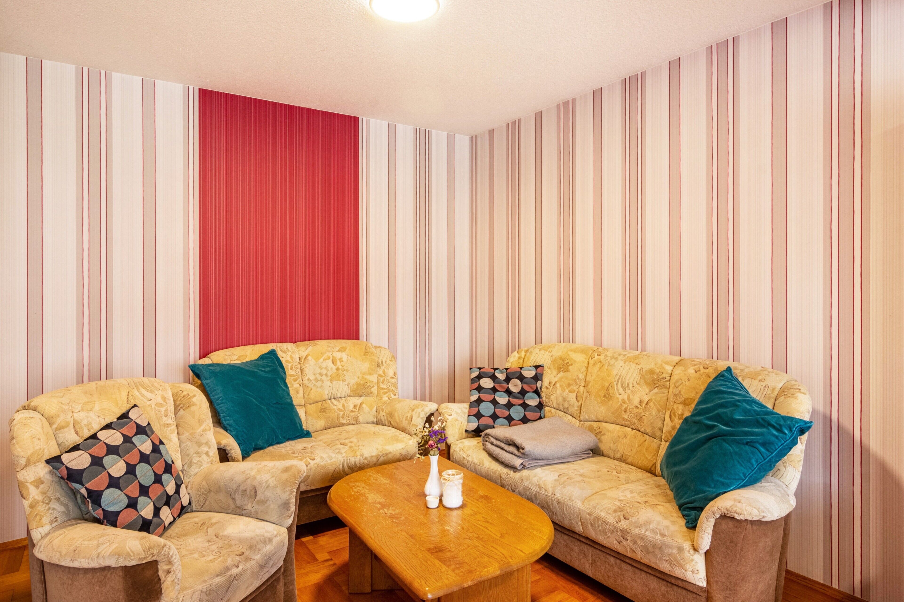 A living room with two patterned sofas, a wooden coffee table, and a red curtain.