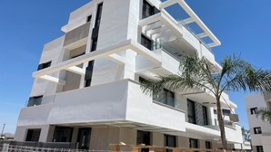 A modern multi-story building with a white facade, balconies, and a clear sky. - Luxury apt, Europe's largest lagoon, heated pool, Santa Rosalia Lake Resort. (MC)
