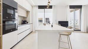 A modern kitchen with white cabinetry, a central island, and a large window providing a view of the cityscape. - Luxury apt, Europe's largest lagoon, heated pool, Santa Rosalia Lake Resort. (MC)