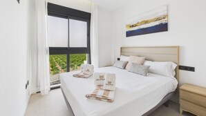 A hotel room with a large bed, two pillows, a bedside table, and a painting on the wall. - Luxury apt, Europe's largest lagoon, heated pool, Santa Rosalia Lake Resort. (MC)