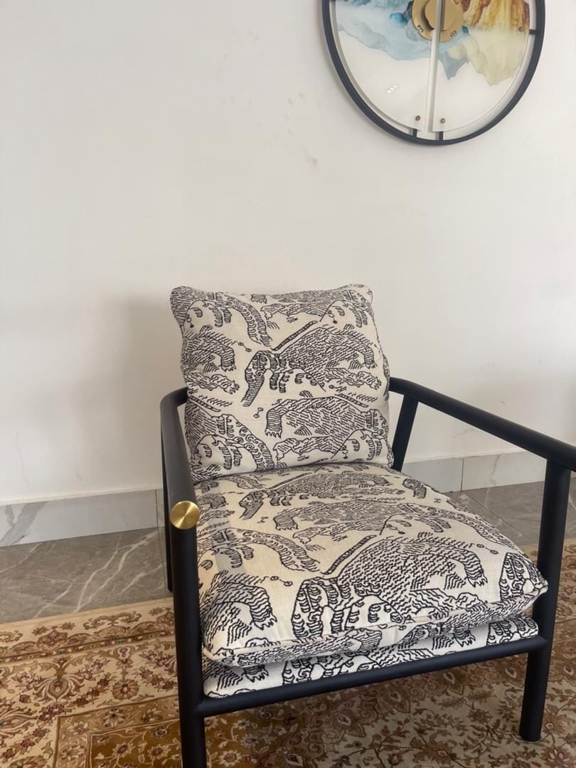 A chair with a patterned cushion and a round wall decoration.