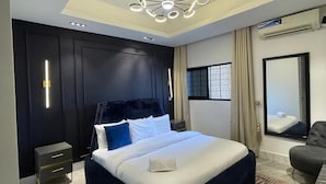 A modern bedroom with a large bed, a unique ceiling light, and a view of the city through a window. - Sujimoto Residences  (Lagos)