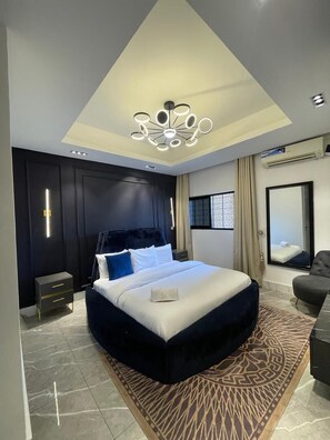 Un dormitorio moderno con una cama grande, una lámpara de techo original y vistas de la ciudad a través de una ventana.